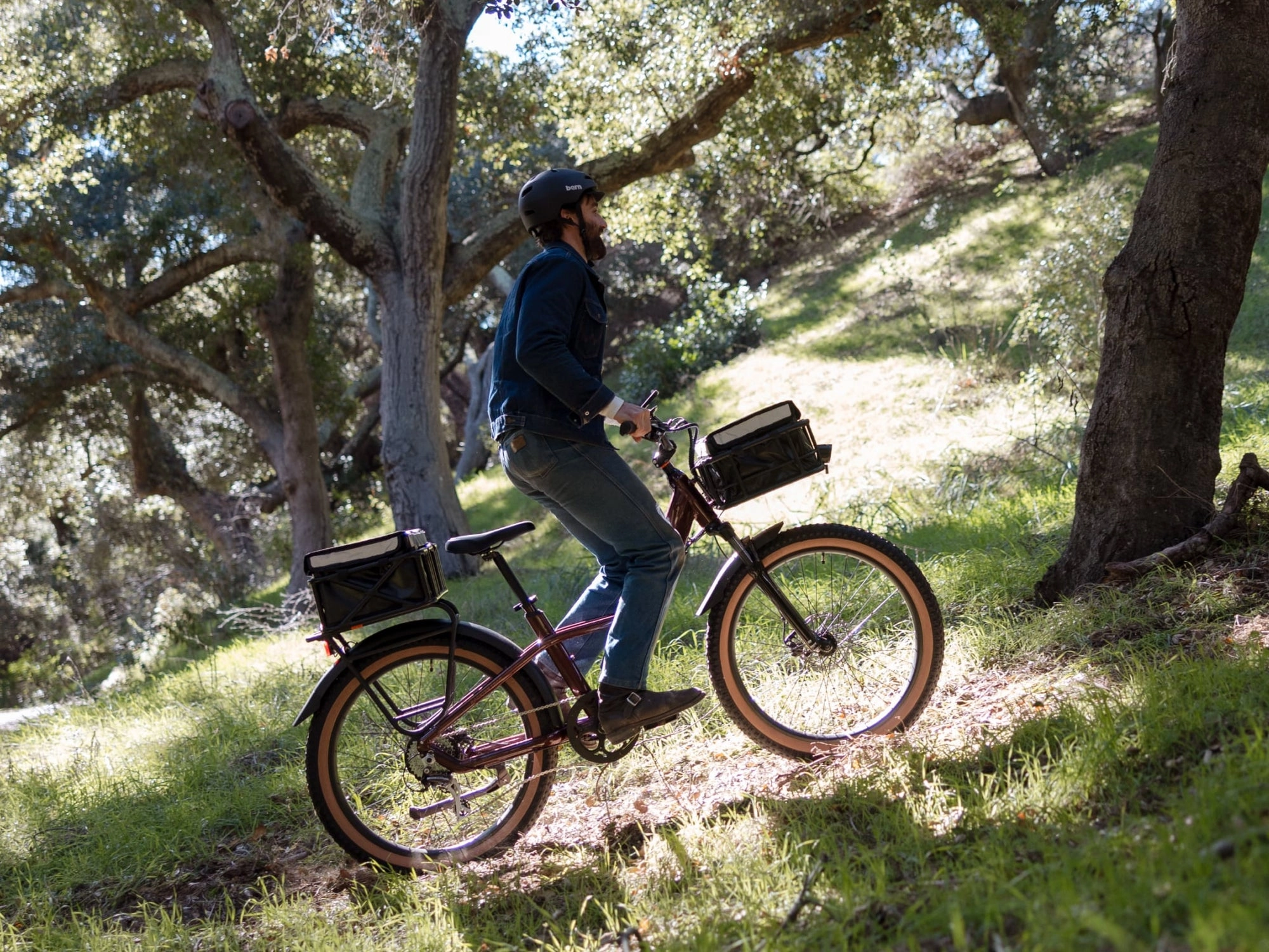 A rider on a copper red Rad Power Bikes ebike pushes up a tree-lined hillside trail