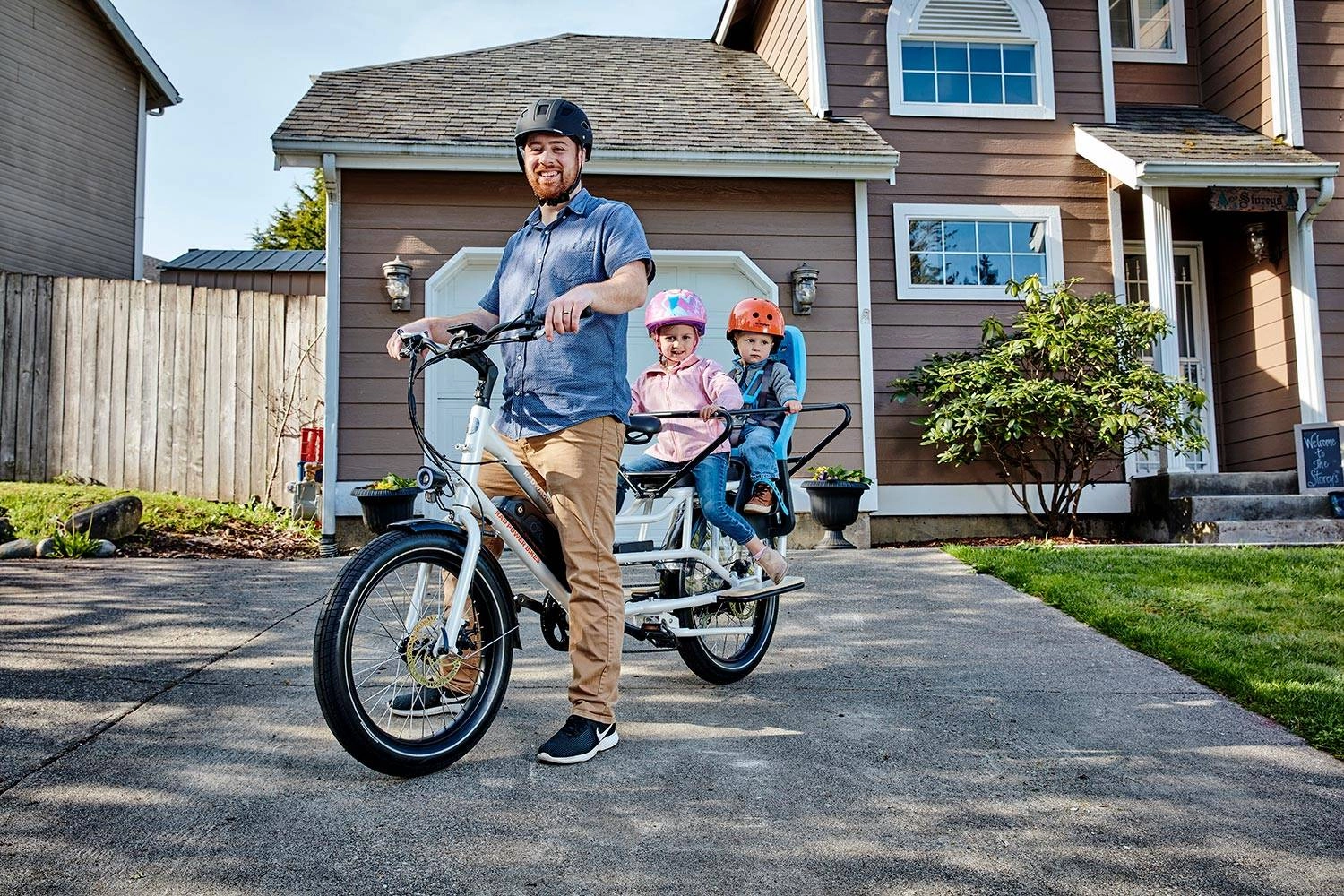 A father with two children on a Rad ebike outside a suburban house